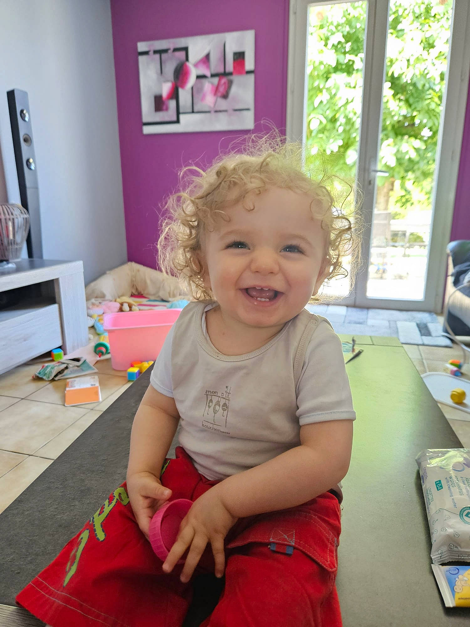 Enzo a rejoint le concours — aidez-le/la à gagner de superbes lots ! baby, baby_toddler_clothing, cheek, child, floor, flooring, fun, happy, joy, lap, magenta, party, person, pink, room, sitting, smile, standing, t_shirt, toddler