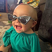 Nevaeh joined the competition — help win amazing prizes! baby, blanket, carpet, child, clothing, cute, fashion, furniture, glasses, hand, happy, home, indoor, living_room, person, playful, portrait, smiling, sunglasses, toddler