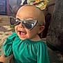 baby, blanket, carpet, child, clothing, cute, fashion, furniture, glasses, hand, happy, home, indoor, living_room, person, playful, portrait, smiling, sunglasses, toddler