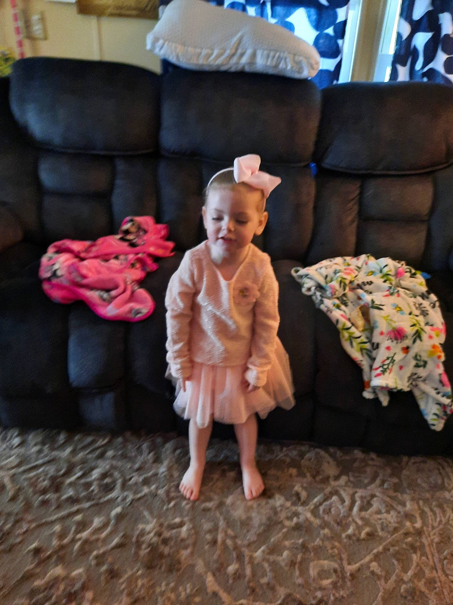 Aurora King is registered to the contest to win money with this photo: barefoot, child, comfort, couch, floor, flooring, foot, fun, furniture, hardwood, human_leg, lamp, leisure, living_room, person, picture_frame, pillow, sitting, smile, toddler