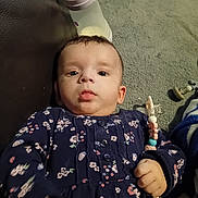 Olga Contulescu participe au concours pour gagner de l'argent avec cette photo : baby, infant, child, floor, carpet, milk_bottle, pacifier_clip, navy_clothing, floral_pattern, hand, face, eyes, indoor, toy, clothing, person, cute, lying_down, expression, young