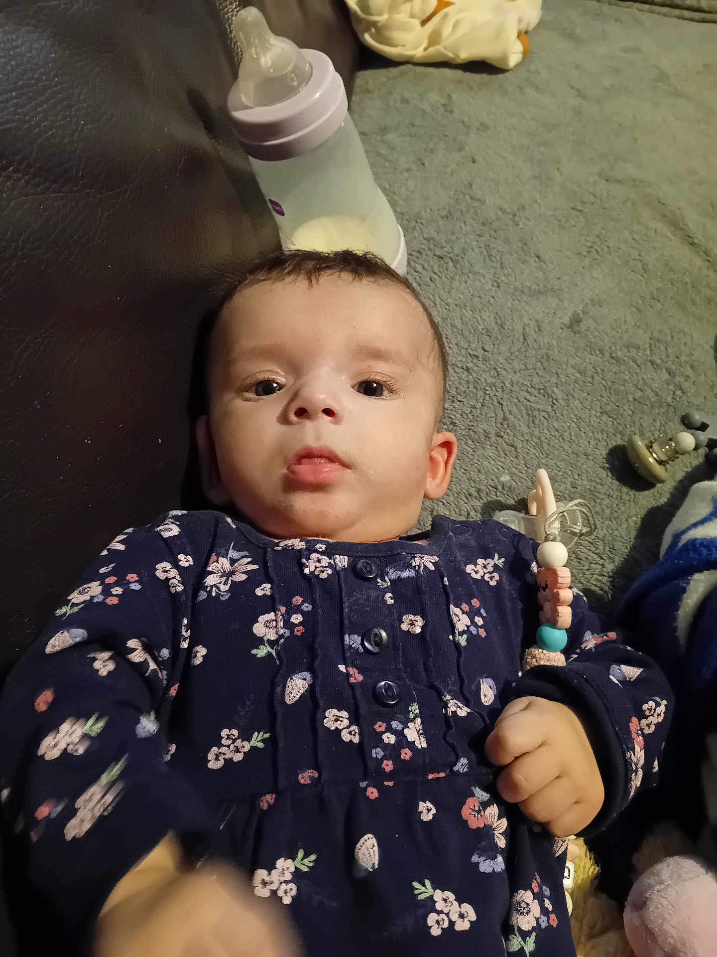 Olga Contulescu participe au concours pour gagner de l'argent avec cette photo : baby, infant, child, floor, carpet, milk_bottle, pacifier_clip, navy_clothing, floral_pattern, hand, face, eyes, indoor, toy, clothing, person, cute, lying_down, expression, young