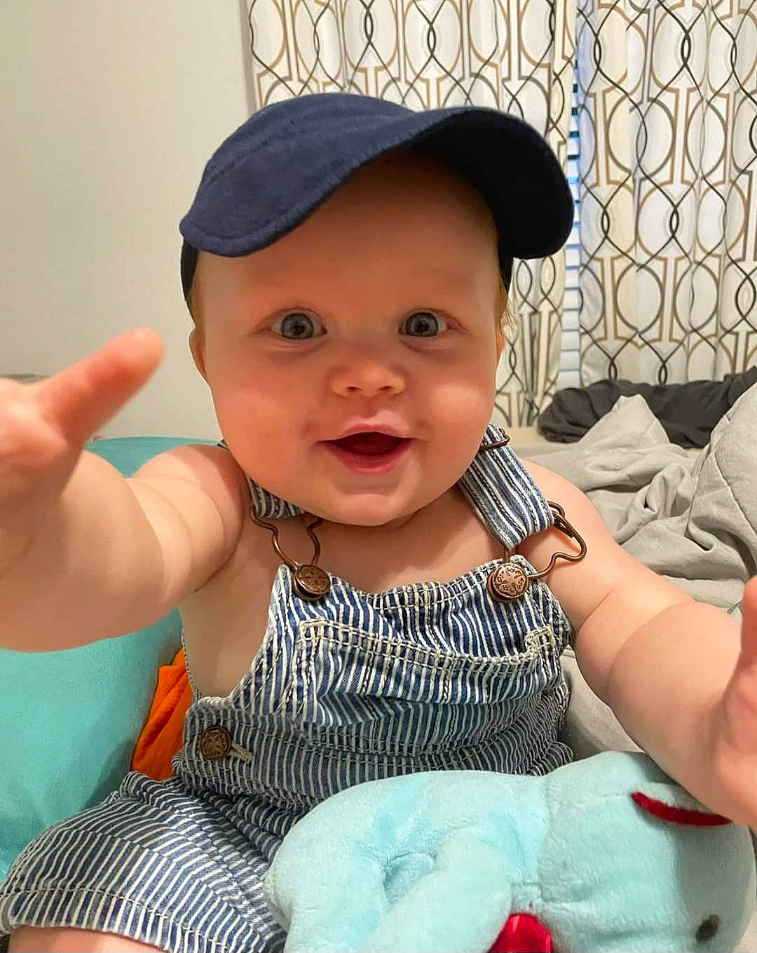 Dayton joined the competition — help win amazing prizes! arm, baby, baby_toddler_clothing, baseball_cap, cap, cheek, child, finger, fun, gesture, hand, happy, headgear, headwear, pattern, person, sitting, skin, sleeve, smile