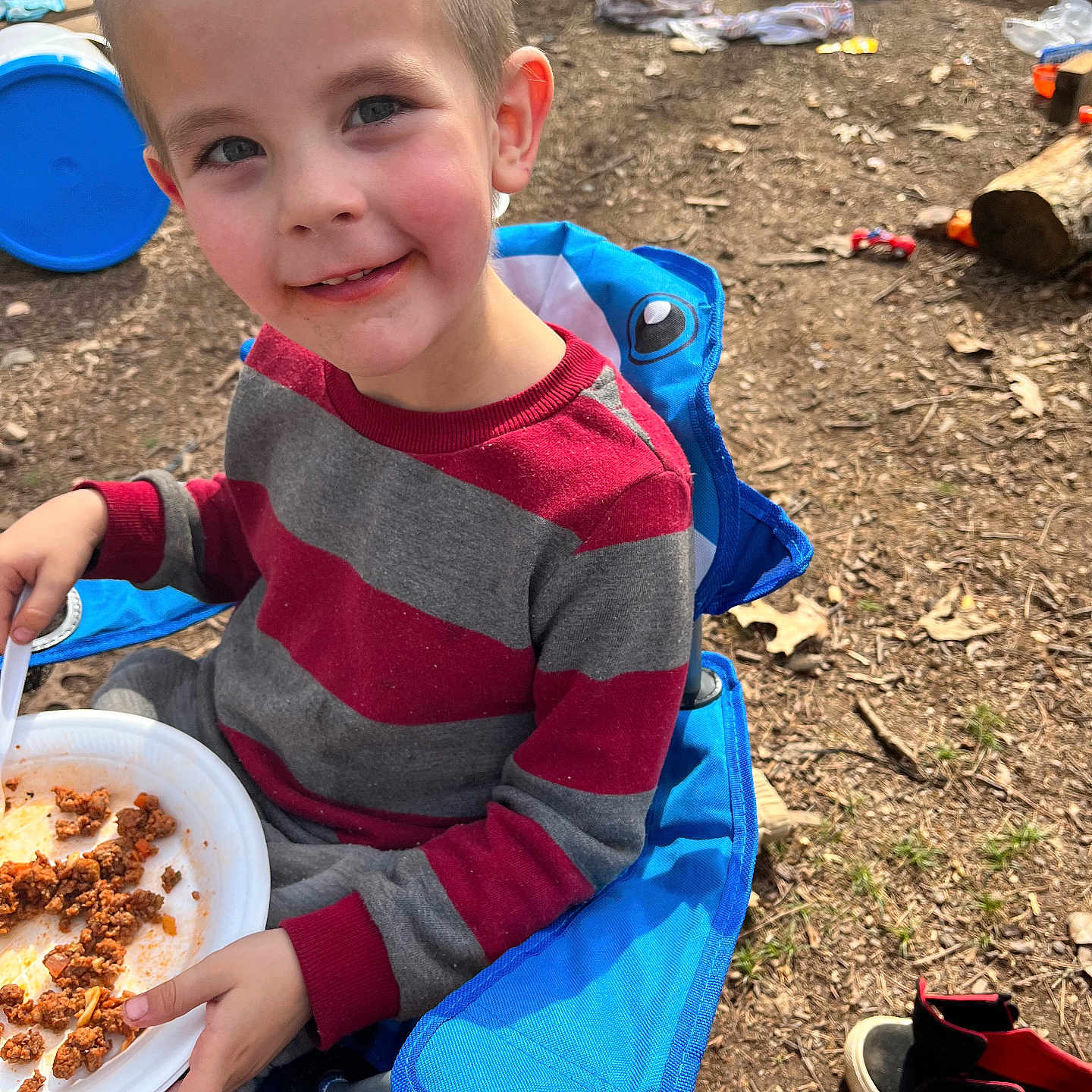 Jeremiah joined the competition — help win amazing prizes! child, boy, outdoor, smiling, chair, blue_chair, plate, food, sweater, red_and_gray, toy, slide, shoes, mickey_mouse, ground, dirt, playground, happy, face, person