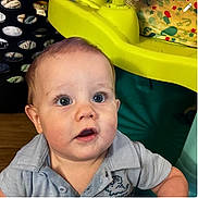 James joined the competition — help win amazing prizes! baby, child, blue_eyes, curious, shirt, dinosaur_print, indoor, toy, yellow, plastic, face, person, infant, young_child, expression, closeup, head, skin, mouth, hair