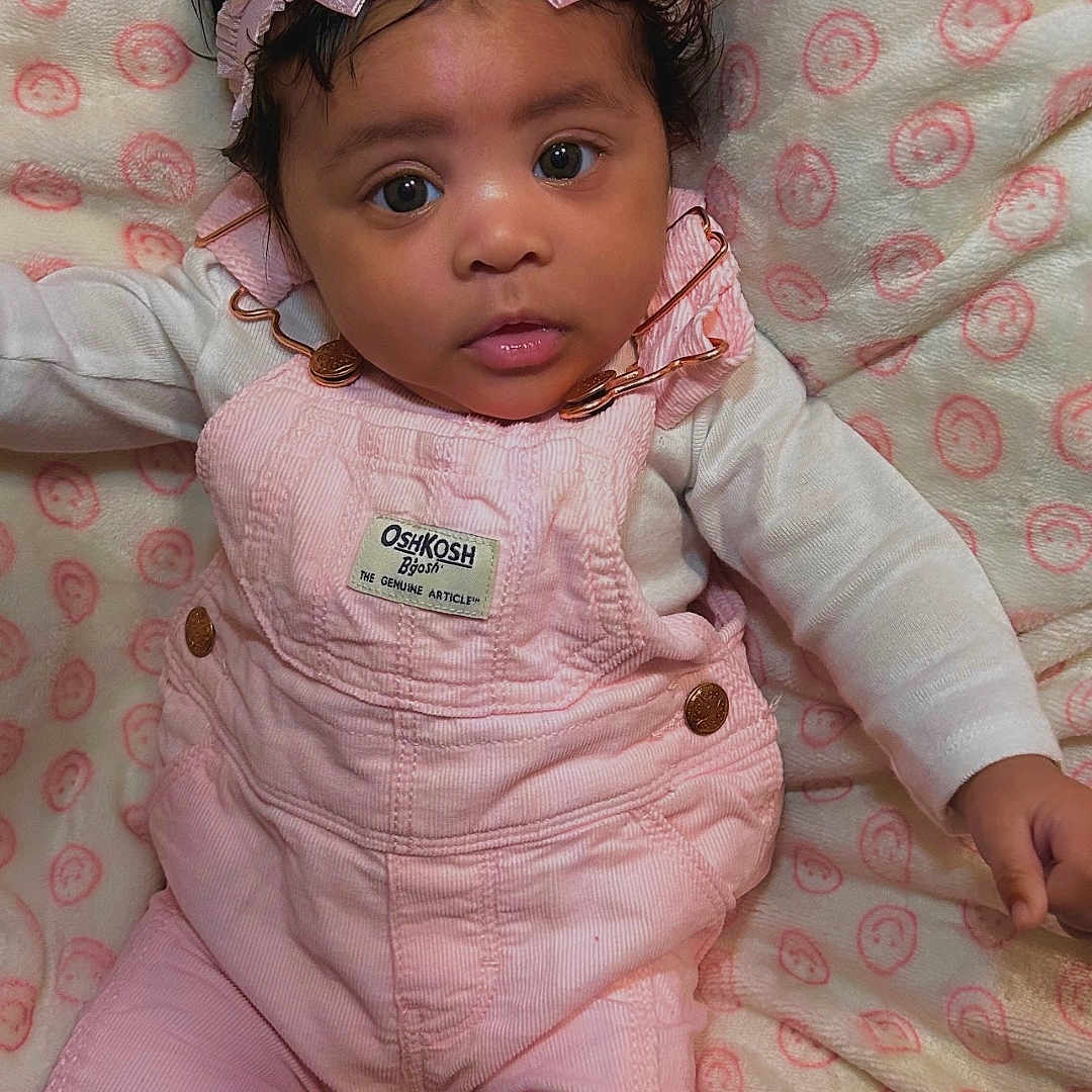 Sariyah is registered to the contest to win money with this photo: accessories, baby, bodypart, bonnet, clothing, coat, couch, dress, face, finger, furniture, hat, head, jacket, jeans, pants, person, photography, portrait, toy