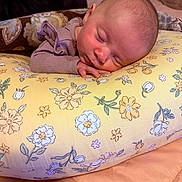 Aerith is registered to the contest to win money with this photo: baby, newborn, sleeping, infant, portrait, face, indoors, cozy, blanket, floral, cushion, pillow, bed, home, peaceful, resting, clothing, purple, close_up, photography