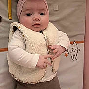 Elia participe au concours pour gagner de l'argent avec cette photo : baby, infant, toddler, headband, flower, vest, white_shirt, brown_pants, cute, face, hands, playmat, cat_illustration, stars, lying_down, indoors, soft_lighting, child, portrait, expression