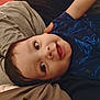 Anthony is registered to the contest to win money with this photo: toddler, child, face, smile, blue_shirt, person, lying_down, eyes, hair, patterned_clothing, arm, fabric, indoor, cozy, close_up, skin, expression, portrait, head, casual