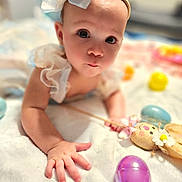Gabriella is registered to the contest to win money with this photo: baby, blanket, bow, child, closeup, clothing, colorful, cute, expression, eyes, face, hand, headband, indoor, infant, playtime, portrait, skin, soft, toy