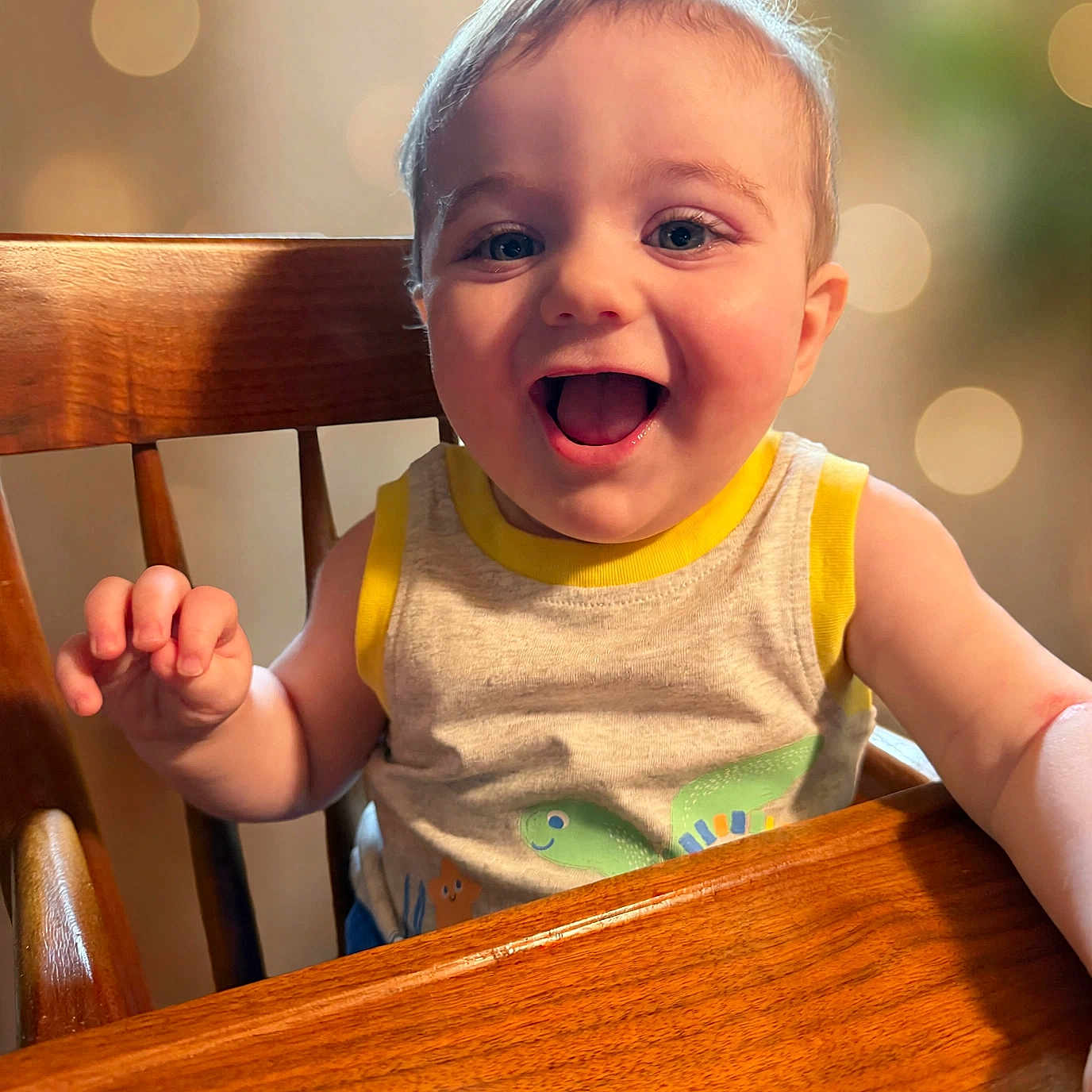 Easton joined the competition — help win amazing prizes! baby, child, high_chair, wood, smile, happy, face, eyes, tank_top, clothing, indoor, person, cute, expression, infant, table, hand, skin, light, bokeh