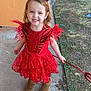 child, girl, costume, devil, red_dress, headband, horns, trident, outdoor, grass, concrete, boots, smiling, happy, person, playful, holiday, cute, portrait, daylight