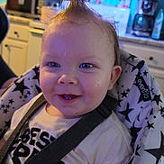 Finn joined the competition — help win amazing prizes! baby, child, smiling, mohawk, high_chair, straps, indoor, kitchen, face, blue_eyes, clothing, person, seat, patterned_fabric, happy, toddler, cute, expression, hair, infant