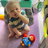 Rayland joined the competition — help win amazing prizes! baby, child, toy, plush_bear, keyboard_toy, purple_blanket, indoor, play_area, cute, smiling, sitting, striped_shirt, soft_light, floor, hand, foot, blond_hair, face, happy, playtime