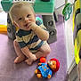 baby, child, toy, plush_bear, keyboard_toy, purple_blanket, indoor, play_area, cute, smiling, sitting, striped_shirt, soft_light, floor, hand, foot, blond_hair, face, happy, playtime