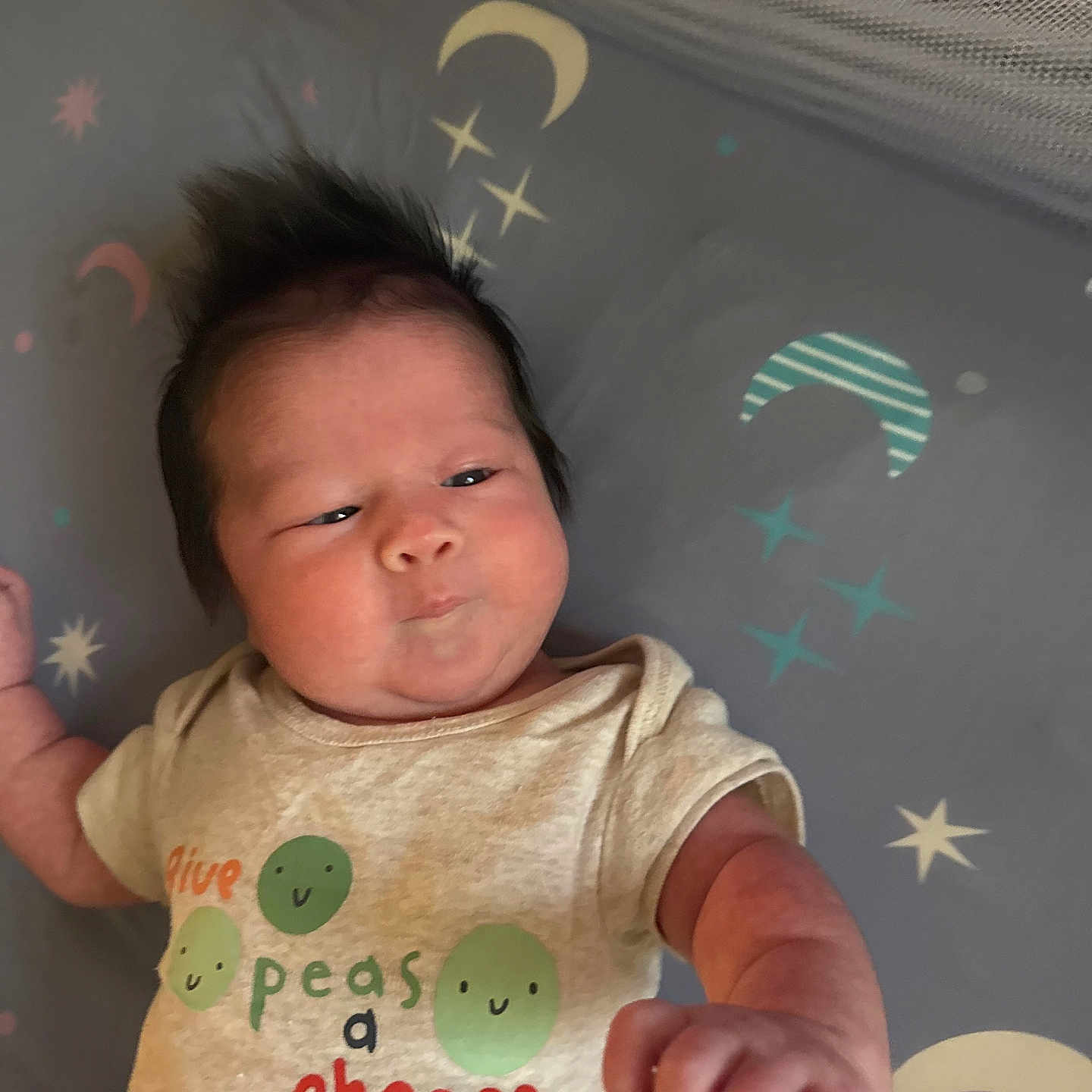 Ryley is registered to the contest to win money with this photo: baby, blanket, child, clothing, cute, expression, face, fist, hair, indoors, infant, lying_down, moon, newborn, pattern, peas, person, shirt, stars, text