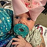 Athena joined the competition — help win amazing prizes! baby, infant, child, portrait, face, pacifier, pink_bow, headband, wide_eyes, looking_at_camera, indoor, blanket, clothing, sitting, close_up, caregiver_hand, tattoo, soft_lighting, adorable, baby_accessories