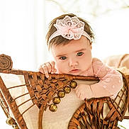 Ena participe au concours pour gagner de l'argent avec cette photo : baby, child, headband, pink, lace, wicker, chair, hand, face, eyes, portrait, indoor, cute, infant, furniture, soft_light, expression, person, young, candid