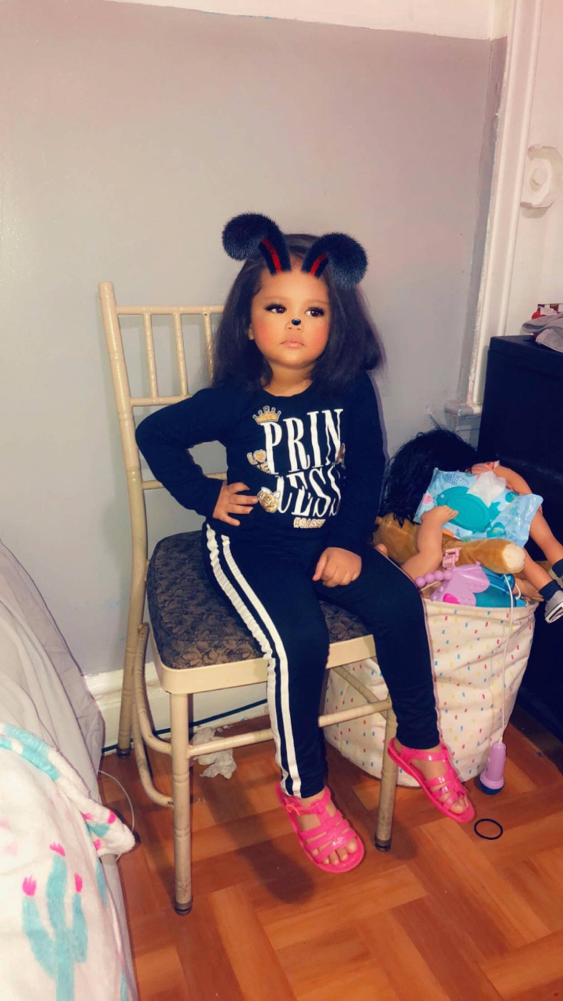 Mariah is registered to the contest to win money with this photo: black_hair, brown_hair, chair, child, doll, ear, fawn, footwear, furniture, joint, leg, long_hair, person, pink, shoe, shoulder, sitting, t_shirt, tights, toddler