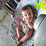 baby, child, infant, smiling, happy, portrait, sitting, bouncer, baby_chair, pacifier, toy, jungle_theme, colorful, indoor, outdoor, concrete_floor, clothing, barefoot, face, watermark