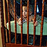 baby, child, infant, crib, crib_rails, nursery, bedroom, wooden_furniture, sitting, gripping, curious, surprised, blue_eyes, short_hair, blanket, mattress, indoor, portrait, cozy, watermark