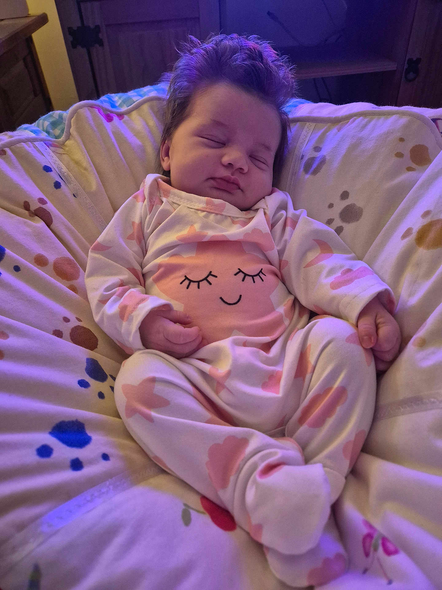 Daisy-Mae is registered to the contest to win money with this photo: baby, sleeping, infant, pajamas, pink, cushion, indoor, child, cozy, soft_lighting, face, hands, footed_pajamas, wooden_furniture, blanket, peaceful, cute, relaxed, home, resting