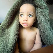 James joined the competition — help win amazing prizes! toddler, child, blanket, green_blanket, indoor, portrait, curious, eyes, skin, face, expression, soft_texture, warm, cozy, young_child, person, baby, candid, naked_torso, natural_light