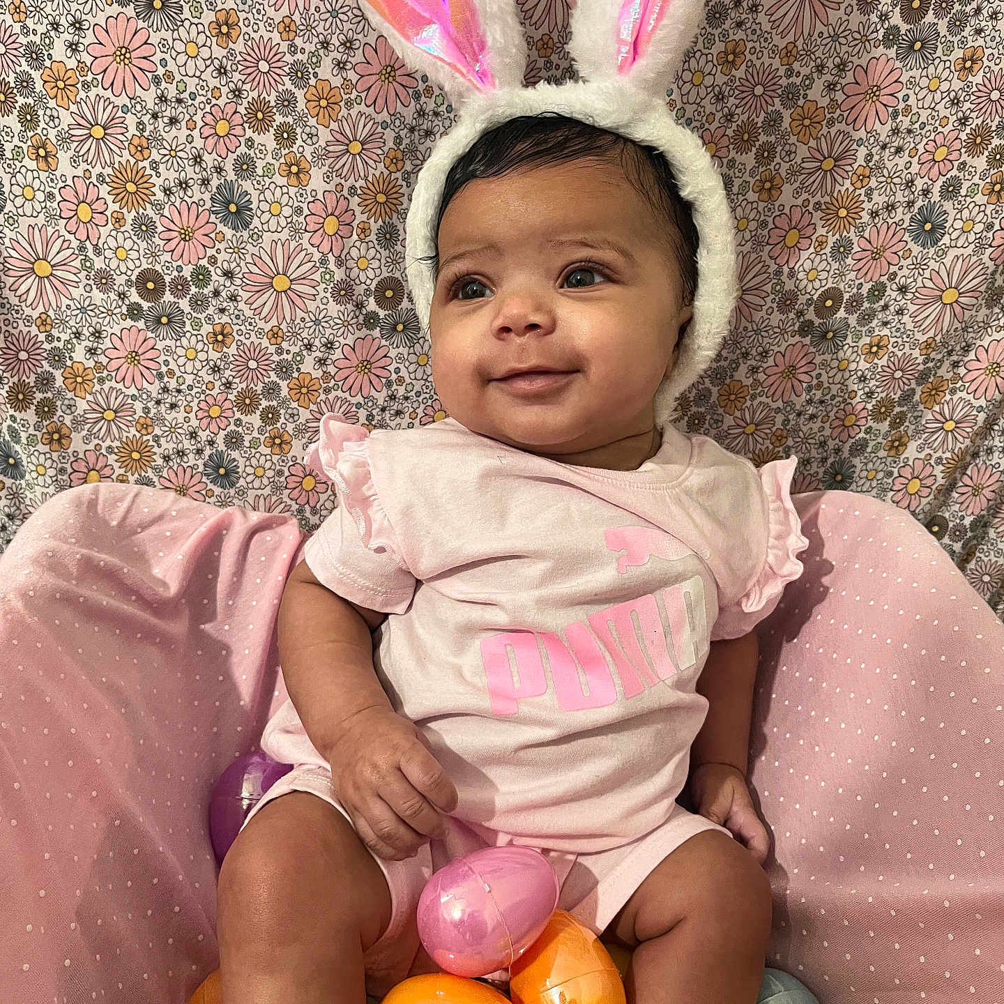 Mailani is registered to the contest to win money with this photo: baby, bunny_ears, child, colorful, cute, easter_eggs, festive, floral_background, happy, headwear, holiday, indoors, infant, pastel_colors, pink_clothing, playful, sitting, smiling, soft_lighting, toy