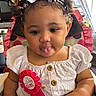 baby, birthday, buttoned_shirt, celebration, child, curly_hair, cute, headband, high_chair, indoors, person, pink, playful, polka_dot, ribbon, seat, smiling, toddler, tongue_out, white_dress