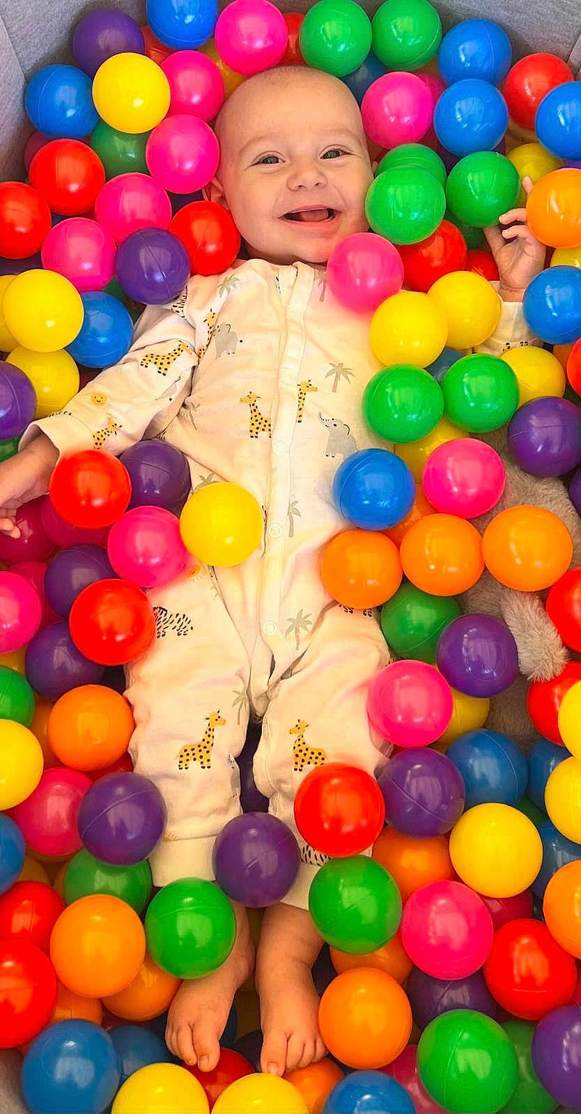 Fin participe au concours pour gagner de l'argent avec cette photo : baby, child, smiling, colorful, plastic_balls, onesie, giraffe_pattern, elephant_pattern, playtime, indoor, happy, cute, feet, hands, face, toy, multicolor, fun, infant, portrait