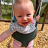 baby, baby_clothing, child, daytime, face, fun, happy, nature, outdoor, person, pink_pants, play, playground, polka_dot, shirt, smiling, sunlight, swing, trees, wood_chips