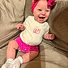 Zella is registered to the contest to win money with this photo: apparel, baby, beige_couch, child, couch, cute, happy, headband, human, indoor, infant, laughing, pink_bow, pink_shorts, polka_dots, portrait, smiling, snail_design, socks, white_onesie