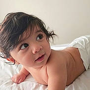 Noah is registered to the contest to win money with this photo: baby, infant, diaper, lying_down, bed, white_bed, curly_hair, dark_hair, cute, child, skin, portrait, indoor, soft_light, looking_away, closeup, happy, toddler, young_child, person