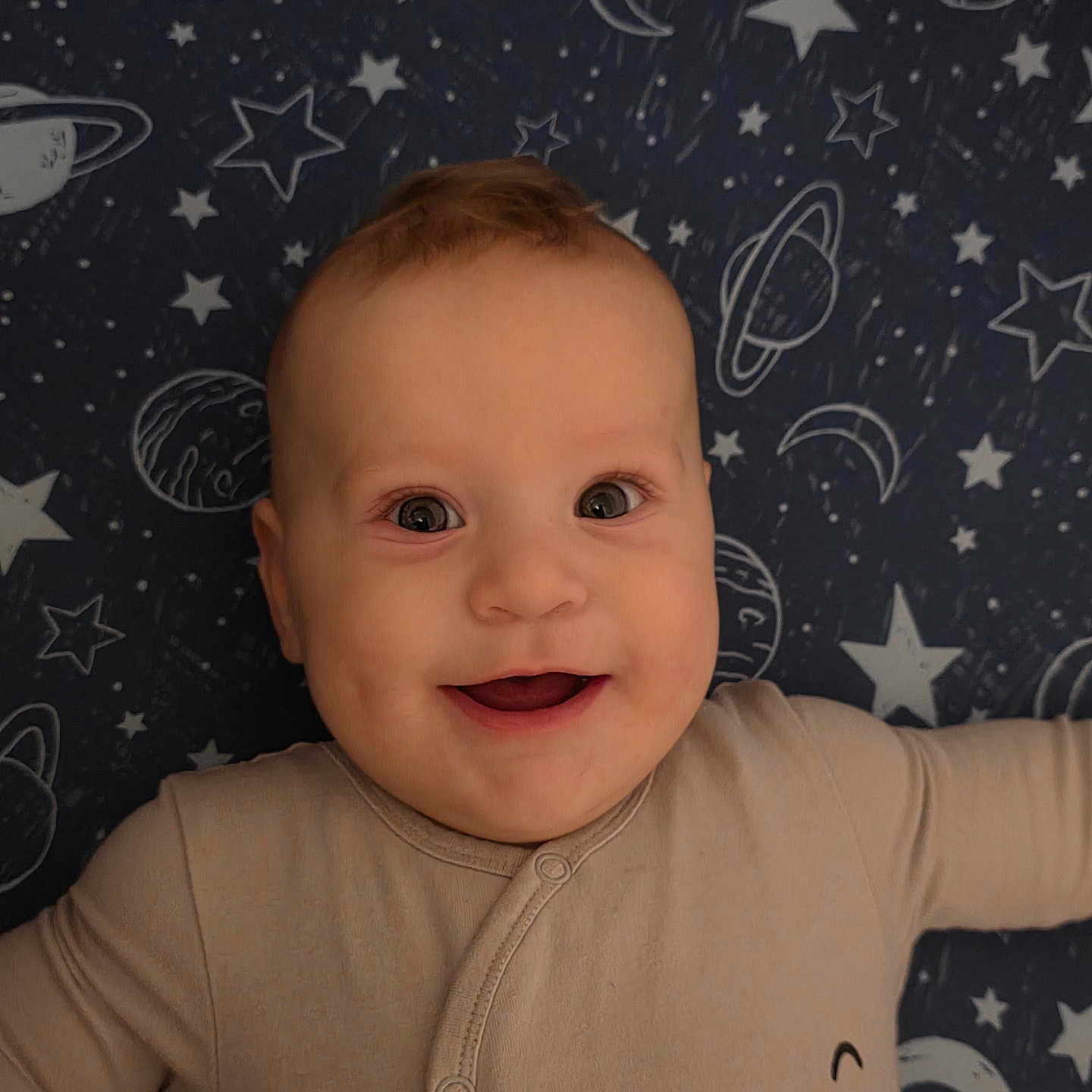 Damian is registered to the contest to win money with this photo: baby, child, closeup, clothing, cosmic_background, cute, expression, face, happy, indoors, infant, light_skin, lying_down, moons, onesie, planets, portrait, short_hair, smiling, stars