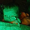 baby, infant, child, face, eyes, pacifier, pacifier_clip, blanket, fuzzy_blanket, sleeping, bed, bedding, portrait, close_up, indoor, night, green_lighting, low_light, cozy, photograph