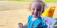 Delilah joined the competition — help win amazing prizes! toddler, child, smiling, curly_hair, blue_shirt, sunglasses, toy_boat, plastic_chair, minnie_mouse, outdoor, daylight, greenery, concrete, play_area, happy, cute, person, summer, sunlight, portrait