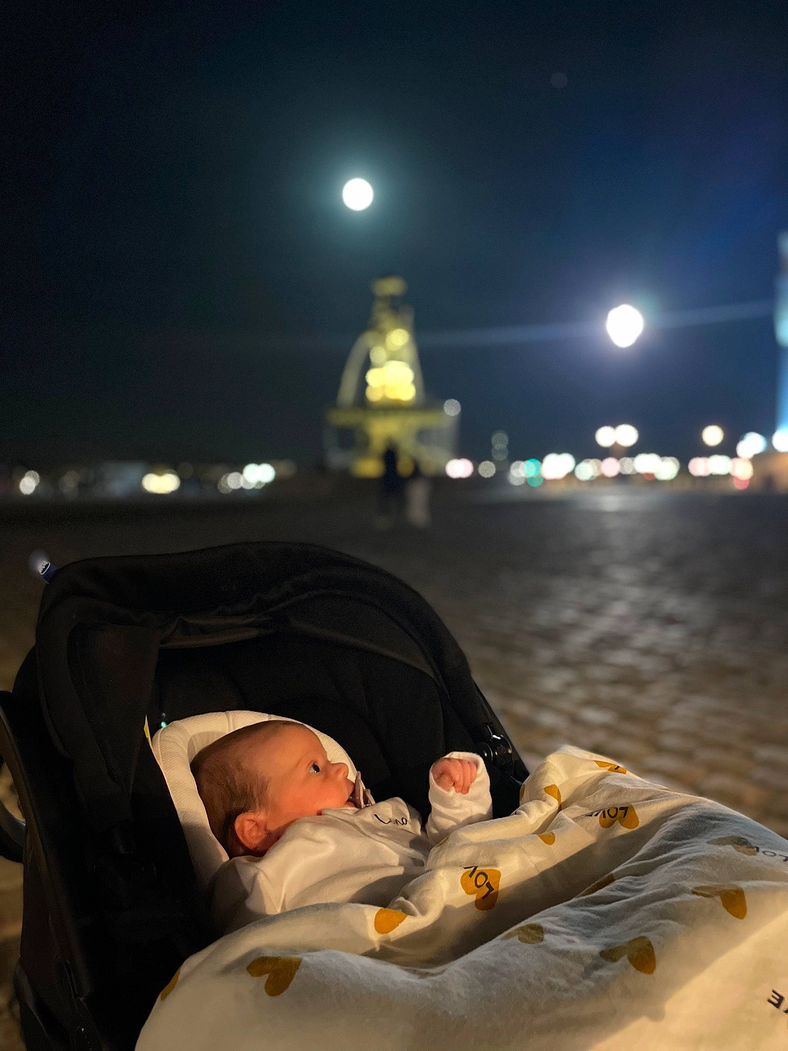 Luna a rejoint le concours — aidez-le/la à gagner de superbes lots ! astronomical_object, baby, baby_products, child, comfort, darkness, event, flash_photography, fun, midnight, moon, night, person, personal_protective_equipment, sitting, sky, street_light, toddler, winter