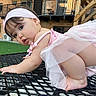 baby, balcony, brick_building, child, crawling, curious, cute, face, foot, grass, headband, infant, metal_table, outdoor, person, pink_clothing, railing, skin, table, tutu