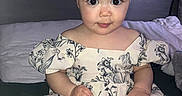 Daynelis is registered to the contest to win money with this photo: baby, bed, child, clothing, cute, dress, expression, face, feet, flower_pattern, hands, headband, indoor, person, pillow, plush_toys, portrait, sitting, stuffed_animals, young_child