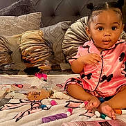 Royalty is registered to the contest to win money with this photo: bed, blanket, child, curious, cute, earrings, foot, hair_buns, hand, indoor, lotion, nail_polish, pajamas, person, pillows, pink, sitting, skin, toddler, toy