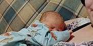Jerry is registered to the contest to win money with this photo: adult, baby, blanket, clothing, comfort, couch, fabric, face, hand, holding, home, indoor, infant, pattern, person, plaid, relaxation, resting, sleeping, smile
