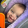 Barbara is registered to the contest to win money with this photo: baby, blue_eyes, car_seat, child, closeup, cute, face, happy, head_support, indoors, infant, orange, person, portrait, purple_cushion, seatbelt, sitting, smile, toy, young