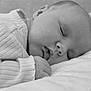 baby, sleeping, infant, close_up, black_and_white, soft_texture, peaceful, face, hand, clothing, blanket, newborn, portrait, resting, cute, young_child, skin, expression, calm, comfort