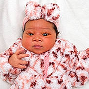 Alora is registered to the contest to win money with this photo: baby, newborn, infant, child, portrait, face, eyes, fluffy_outfit, pink_clothing, white_clothing, hat, pom_pom, blanket, cozy, lying_down, indoors, soft_background, close_up, hands, photography