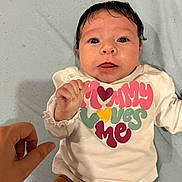 Edyn joined the competition — help win amazing prizes! baby, infant, newborn, face, eyes, hair, hand, adult_hand, onesie, text_on_clothing, mommy_loves_me, colorful_text, white_onesie, mustard_pants, blanket, lying_down, portrait, looking_at_camera, cute, indoor