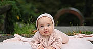 Dolly is registered to the contest to win money with this photo: baby, infant, knitted_clothing, pink, blanket, outdoor, nature, grass, portrait, cute, child, face, headwear, crawling, happy, young, soft_light, closeup, warm_clothing, smiling