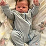 baby, infant, onesie, striped_clothing, blanket, soft_toy, cute, smiling, happy, lying_down, raised_arms, spiky_hair, indoor, child, face, footed_pajamas, pink_details, cozy, comfort, portrait