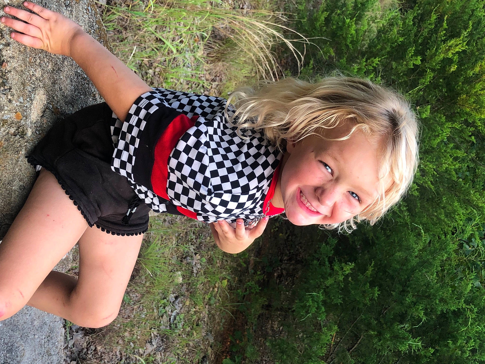 Embyr is registered to the contest to win money with this photo: facial_expression, fun, grass, hair, hand, happy, human_body, joy, knee, leaf, nature, people_in_nature, person, plant, shorts, smile, summer, sunlight, thigh, toddler