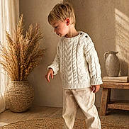 Manoé participe au concours pour gagner de l'argent avec cette photo : child, boy, sweater, white_sweater, beige_pants, sneakers, indoor, woven_rug, woven_vase, dried_plants, wooden_bench, ceramic_jug, natural_light, curly_hair, floor, wall, cozy, casual_clothing, standing, thoughtful