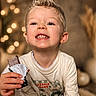 Manoé participe au concours pour gagner de l'argent avec cette photo : child, boy, smiling, chocolate, snack, food, happy, portrait, indoors, casual_clothing, long_sleeve, blonde_hair, spiky_hair, teeth, hand, bokeh, warm_lighting, cozy, background, cute